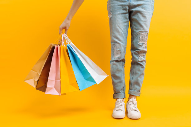 一张腿部的图片，一个女人在购物后的小摊上有很多不同颜色的袋子，背景是黄色图片下载