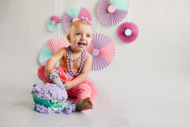 笑容可掬的寿星被涂到了蛋糕上。第一个蛋糕。第一块蛋糕的使用。砸蛋糕。假日装饰照片拍摄粉碎蛋糕图片下载