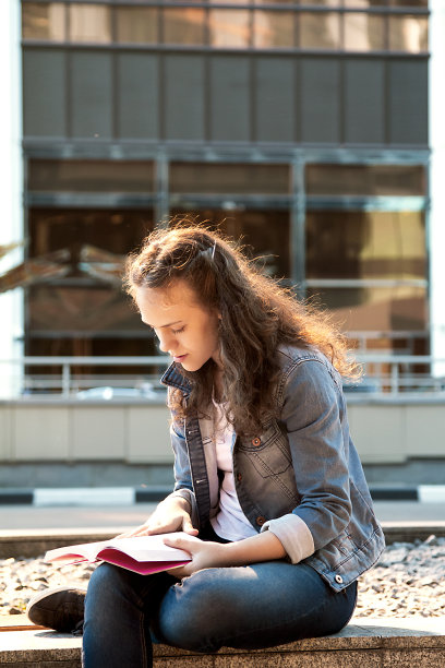 一个女学生在大城市的地上看书图片下载