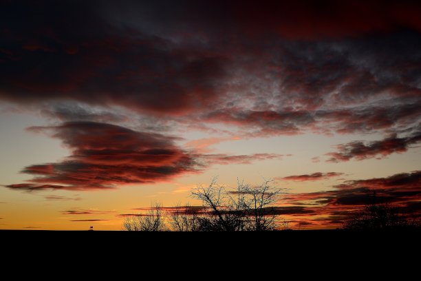 夕阳与猎人隐藏在地平线上。傍晚的图片与美丽的红色天空，树木和隐藏在背景图片下载