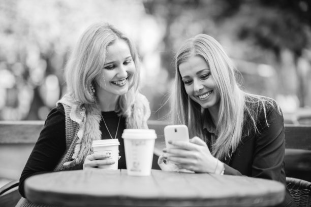 两个漂亮女孩在城里散步。女孩们喝着咖啡，享受着生活图片下载