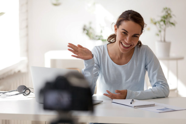 微笑美丽的女人挥舞着她的手看着相机图片下载
