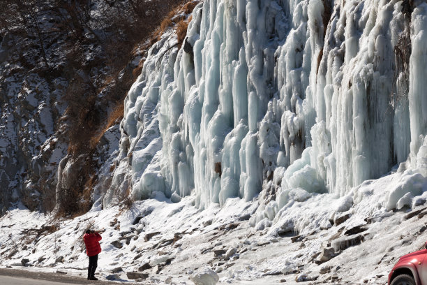 身穿红色羽绒服的男子拍下了冰山瀑布的照片图片下载