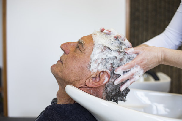 美发师在老人的头发上涂洗发水图片下载