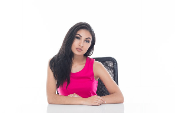 美丽的拉丁女性坐在一张白色的桌子上，看起来很严肃图片下载