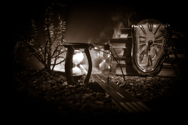 时间的概念。一个男人的剪影站在沙漏中间，在黑暗的背景上有烟雾和灯光。超现实主义的装修图片图片下载