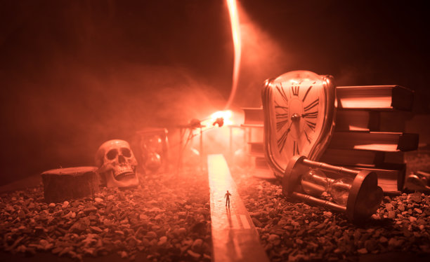 时间的概念。一个男人的剪影站在沙漏中间，在黑暗的背景上有烟雾和灯光。超现实主义的装修图片图片下载