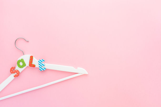 粉红色背景上印有促销文字的白色衣架图片下载