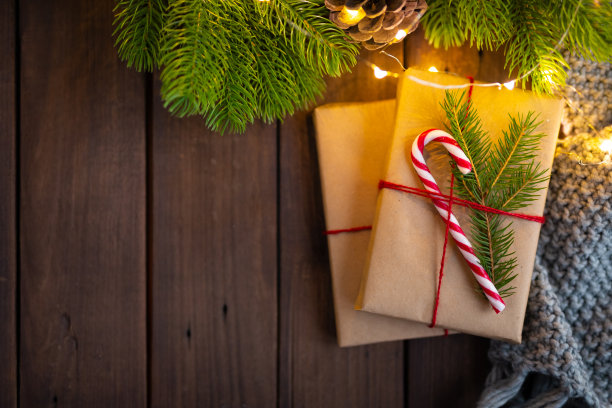 舒适的冬天在冷杉树下的圣诞照片。用牛皮纸包裹的礼物，用糖果手杖装饰在质朴的深色木桌上。圣诞节的概念。新年的概念。礼物。礼物。节日的概念。前视图。自由空间。空间的文本。图片下载