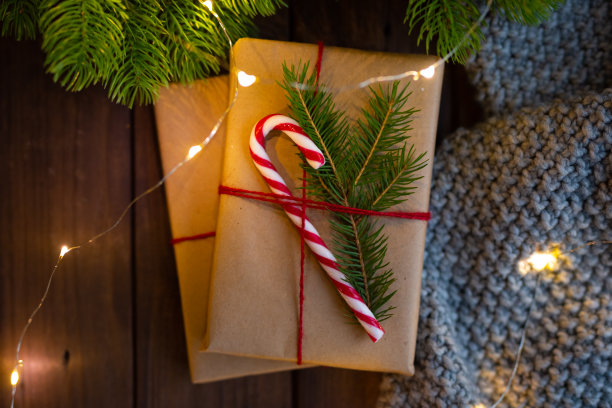 特写镜头。温馨的冬日圣诞照片。用牛皮纸包裹的礼物，用糖果手杖装饰在质朴的深色木桌上。圣诞节的概念。新年的概念。礼物。礼物。节日的概念。前视图。图片下载