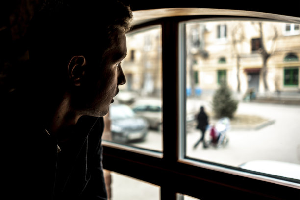 坐在窗前的年轻人的肖像或剪影图片下载