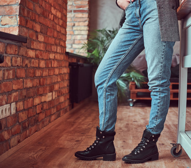 裁剪照片的一个年轻女子穿着灰色优雅的夹克和牛仔裤在房间阁楼的内部。图片下载