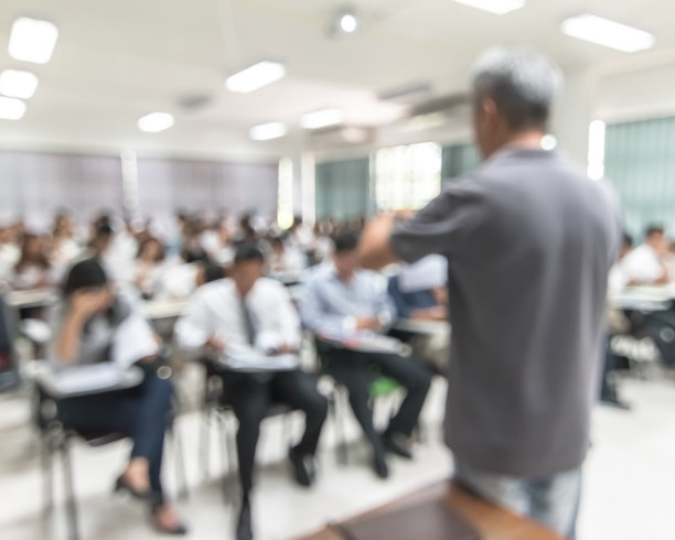 模糊背景的大学学生坐在讲座教室与后排老师在教室前面图片下载