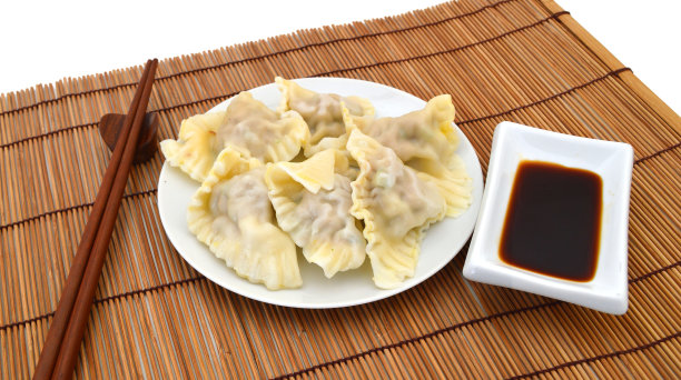 在竹席上放一盘馄饨，配上筷子和蘸酱。选择性聚焦和刻意的浅景深的效果。图片下载