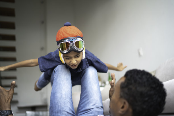 戴着飞行员眼镜的男孩在家和他的爸爸玩飞行图片下载