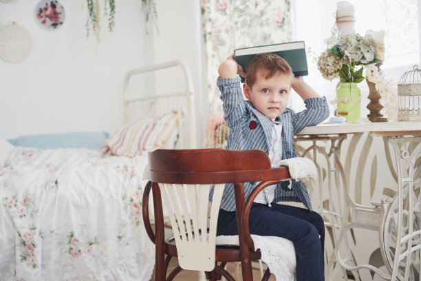 这张照片是一个勤奋的男孩，头上戴着一本书在做作业图片下载