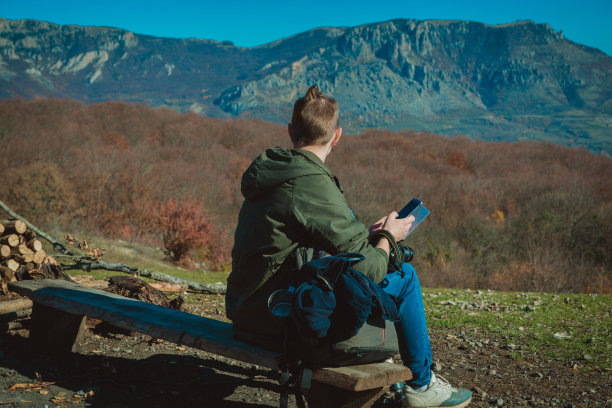 一个穿着远足服装的年轻人坐在高山上图片下载