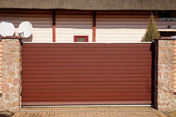 一扇长长的棕色金属门和街道上的一块石头栅栏图片下载