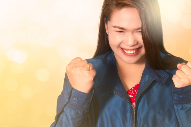 亚洲女人用拳头举起手势在模糊的散景背景，成功，庆祝胜利，成就和获胜的概念图片下载