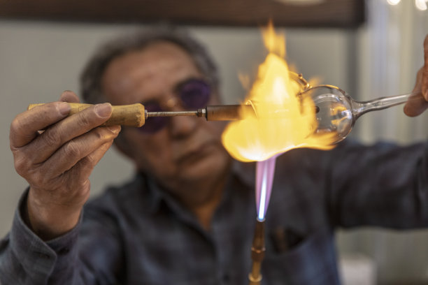 近宏玻璃吹风机工作与火焰上的手工葡萄酒杯从珍贵的水晶在一个车间。手工概念，高品质，工匠，土耳其伊斯坦布尔制造，玻璃吹制。图片下载