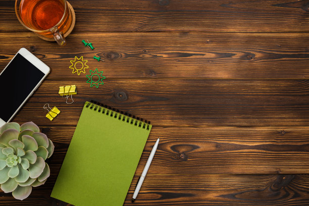 俯视图商务办公桌。笔记本，铅笔，茶杯，植物，手机，回形针木桌子的背景。——图片图片下载