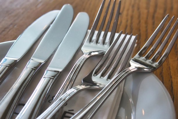 餐馆里桌上闪亮的餐具(刀叉)和陶瓷盘子图片下载