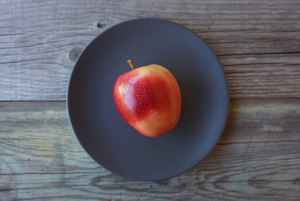 旧木桌上深色盘子上放着红苹果图片下载