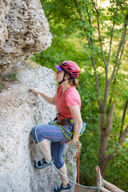 年轻的女运动员戴着红色的头盔爬山的侧面照片图片下载