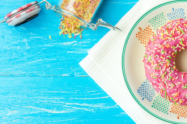 油炸圈饼放在盘子里，厨房毛巾和蓝色的木桌上。糖果的照片与copyspace。前视图。图片下载