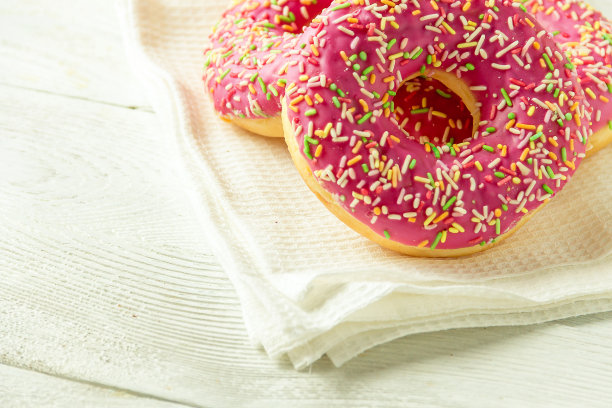 甜甜圈放在厨房的毛巾和木桌上。糖果的照片。图片下载