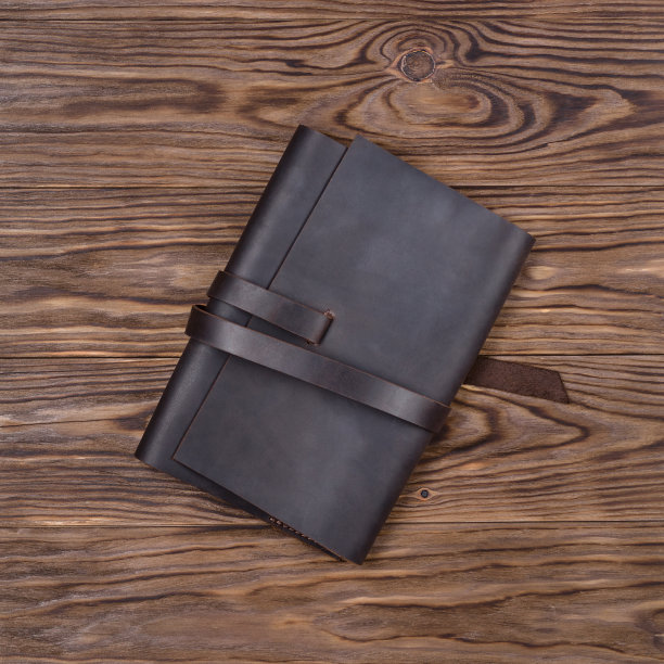 棕色手工皮革笔记本封面上的木制背景。奢侈品商务配件库存照片。图片下载