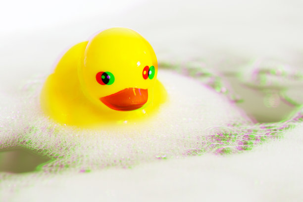一只带有肥皂泡的黄色橡皮鸭，带有泡泡的浅色背景。孩子水疗概念。儿童洗澡时间概念。数字信号故障效应(rgb移位、切片)。屏幕上的错误图片下载