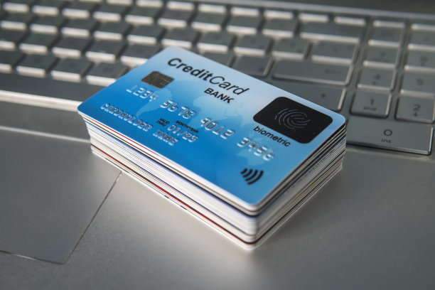 笔记本键盘上一堆塑料信用卡。使用生物识别卡进行网上购物。表面有手指传感器的支付卡。新一代支付系统。堆栈。图片下载