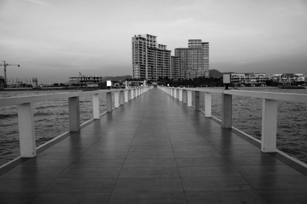 黑色和白色的风景在热带海滩上的桥和建筑和日落天空的背景图片下载
