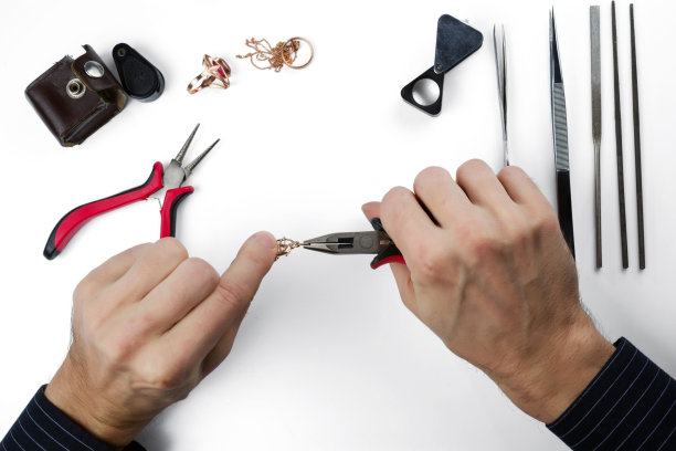 修理黄金首饰。珠宝商的手与工具和珠宝隔离在白色图片下载