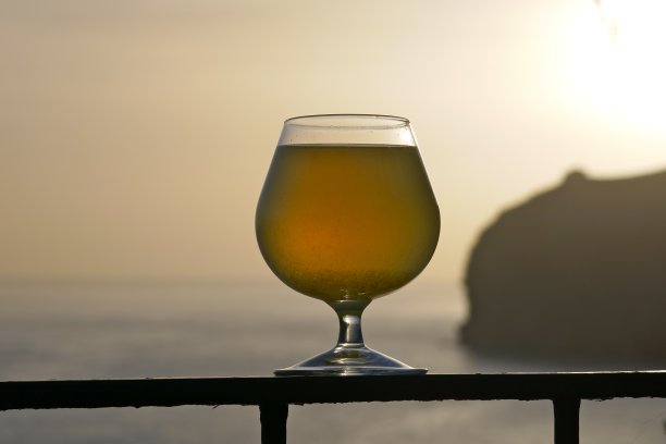 一杯Poncha日落在马德拉与岩石海岸美景图片下载