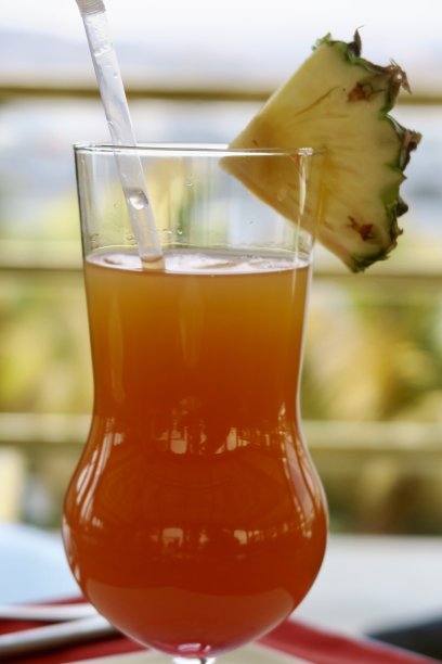 “橙色日落”不含酒精的鸡尾酒/鸡尾酒饮料在节日的飓风杯与菠萝装饰和稻草，印度酒吧背景照片图片下载