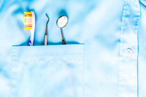 特写的牙科工具，牙刷和镜子在白色医疗制服口袋。口腔及口腔健康理念。图片下载
