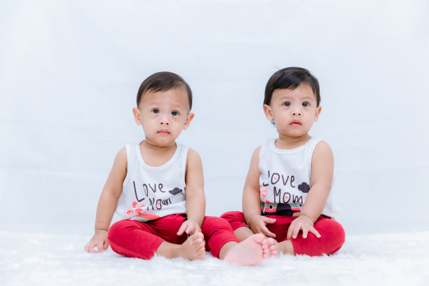 刚出生的双胞胎坐下。新生婴儿双胞胎坐在床上。可爱的新生儿宝宝坐在床上。图片下载