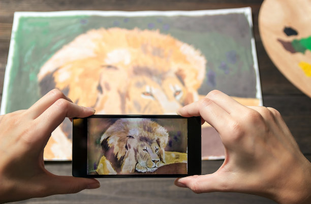 电话里有狮子的照片。在背景上画画，在手机上移动。图片下载
