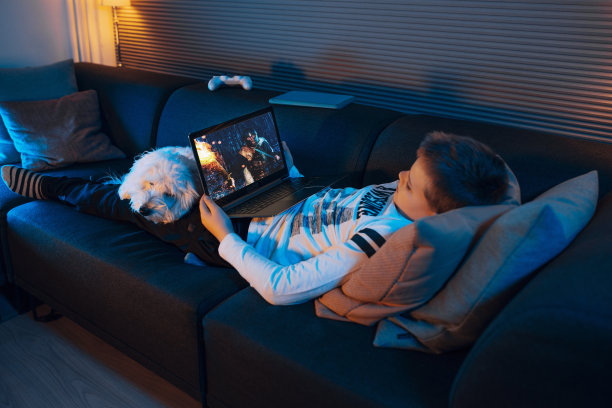 孩子晚上躺在沙发上用笔记本电脑看电影图片下载