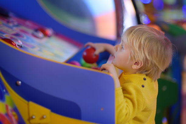 小男孩在游乐中心玩得很开心。在游乐场中心玩老虎机的孩子。图片下载