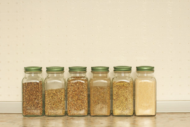 在厨房的灯光背景上，玻璃罐里的香料。罗勒，牛至，意大利香草。为你的文本复制空间图片下载