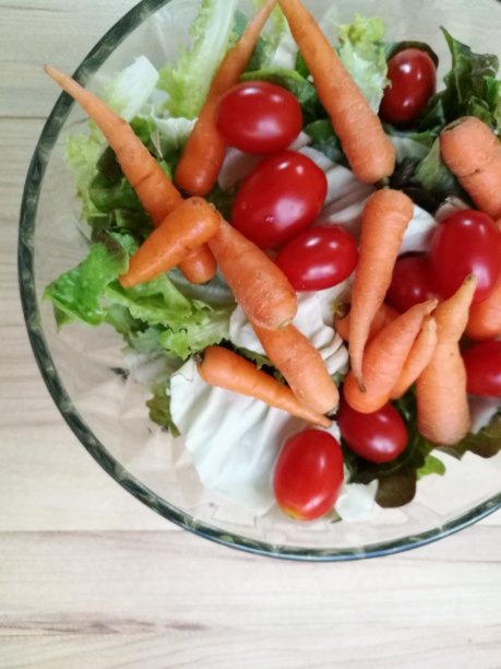有机新鲜沙拉放在玻璃碗里。西红柿，胡萝卜和生菜是健康的菜单。图片下载