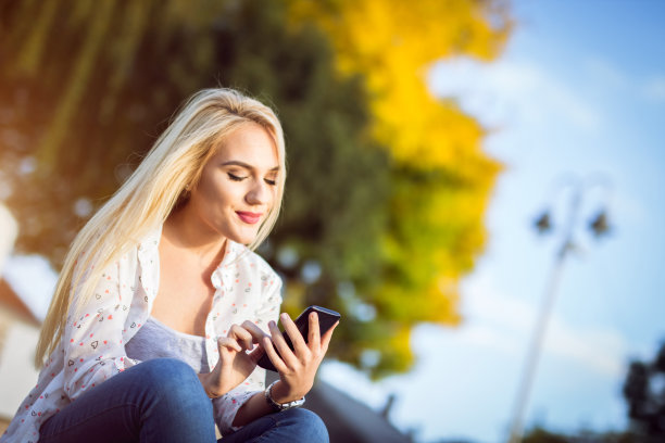 公园高原上的金发女孩用智能手机倾斜图片下载