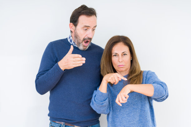 美丽的中年夫妇在孤独的背景下匆匆的指着手表时间，不耐烦，心烦和愤怒的最后期限延误图片下载