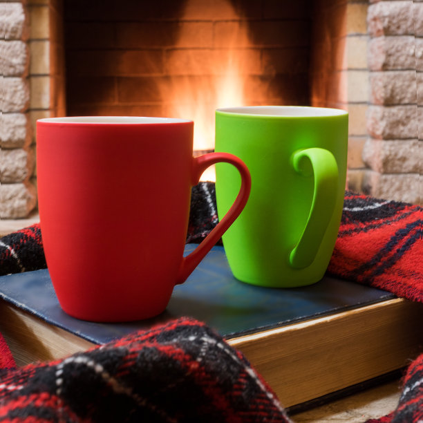 温馨的场景靠近壁炉，两杯热茶，暖和的围巾和书。图片下载