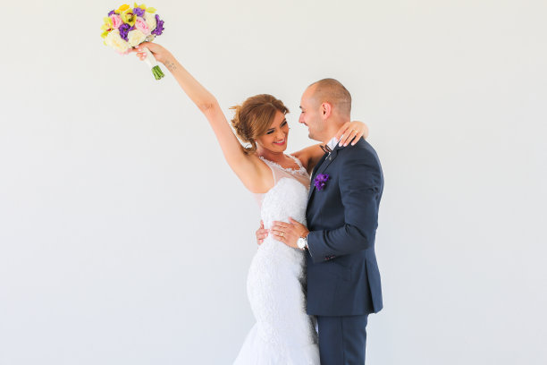 一对美丽的新婚夫妇在白墙前摆姿势图片下载