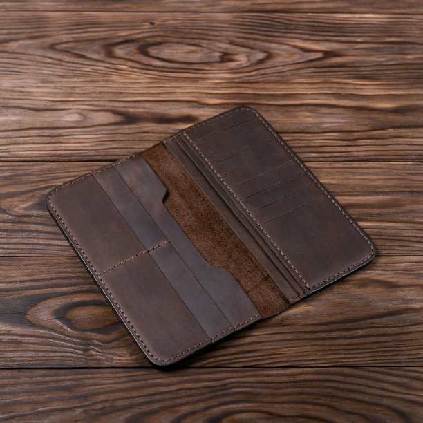 棕色手工皮革门摩奈木纹理背景。钱包被打开了，里面是空的。侧视图。奢侈饰品的库存照片。图片下载