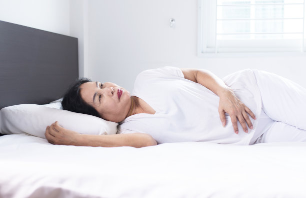 失眠症在上了年纪的亚洲妇女在她的卧室，女性躺着遭受头痛图片下载